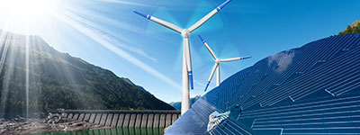 Photovoltaikanlage auf einem Dach und im Hintergrund Windräder zur Erzeugung Erneuerbarer Energie.