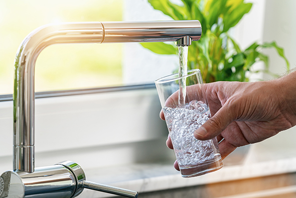 Stockfoto: Trinkwasser aus dem Wasserhahn fließt in Glas