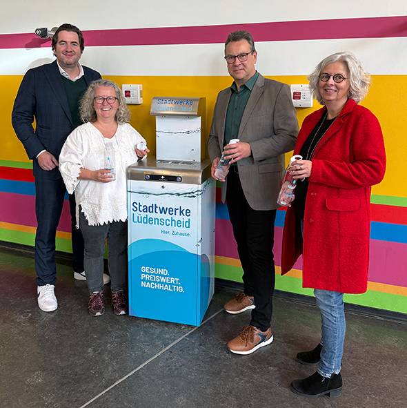Ein Foto der offiziellen Inbetriebnahme des neuen Wasserspenders in der Primusschule Schalksmühle (von links nach rechts) Alexander ten Hompel (Stadtwerke Lüdenscheid, Leiter Marketing / Kommunikation), Anja Krause (stellvertretende Schulleiterin Primusschule Schalksmühle) Volker Neumann (Geschäftsführer Stadtwerke Lüdenscheid) und Anja Wolf (Leiterin Fachbereich Bildung, Kultur und Sport der Gemeinde Schalksmühle)
