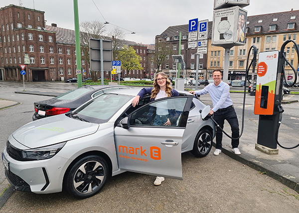 Ein Foto des symbolischen ersten Ladevorgangs an der neuen Schnellladesäule auf dem Parkplatz am Emilienplatz: Melina Zoe Hohmann und Harry Wiens, beide Mark-E, Team Elektromobilität.
